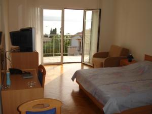 a bedroom with a bed and a television and a balcony at Apartments Petricevic in Selce