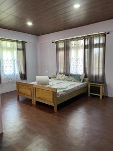 ein Schlafzimmer mit einem großen Bett und zwei Fenstern in der Unterkunft KHIMSHA HOMESTAY in Pelling