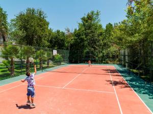 two children playing tennis on a tennis court at Lykia Botanika Beach Fun & Club - All Inclusive in Fethiye