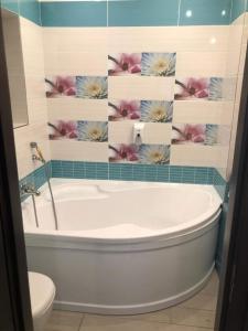 a bath tub in a bathroom with flowers on the wall at Mosoly Szallashely in Szeged
