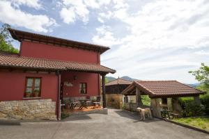 a red house with a dog standing in front of it at Casa Vacacional Miyares in La Estrada