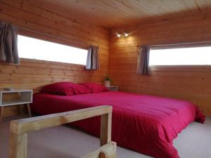 a bedroom with a red bed in a log cabin at Le Petit Chalet de Nîmes Shantay Youstay in Nîmes