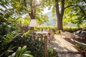 a patio with a table and chairs under a tree at Donauwirt - Hotel garni in Weissenkirchen in der Wachau