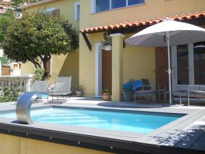 a swimming pool with an umbrella next to a house at STUDIO INDEPENDANT LA TURBIE in La Turbie