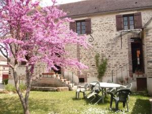 un árbol con flores rosas delante de un edificio en Gîte l'École Buissonnière en Chéu