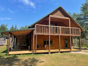 eine große Holzhütte mit einer Veranda und einer Terrasse in der Unterkunft Holiday Home Atmatas in Sabile