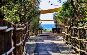 a wooden walkway leading to a park with trees at Camping Village Santapomata in Castiglione della Pescaia