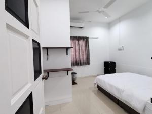 a white bedroom with a bed and a television at SingLeisure Holiday House in Mersing