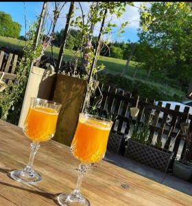 two glasses of orange juice sitting on a wooden table at Riverwood Cottage Stanhope in Stanhope