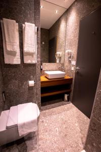 a bathroom with a sink and a toilet and a mirror at Hotel Das Zeit in Lenzing