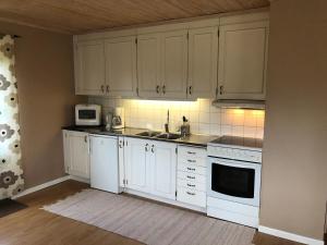 a kitchen with white cabinets and a sink and a microwave at Gården Ekön in Forserum