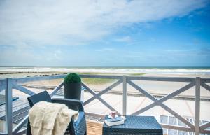 a chair on a balcony with a view of the beach at La Goélette, Chambres d'Hôtes in Wimereux