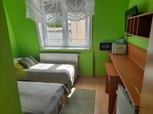 a green room with two beds and a window at Pokoje Gościnne POD DELFINKAMI in Ustka