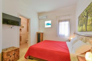 a bedroom with a bed with a red blanket at Calasole Country House in Torre Lapillo