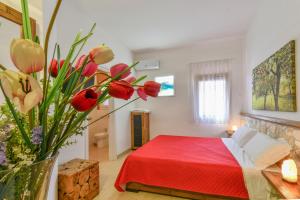 a bedroom with a red bed and a vase of flowers at Calasole Country House in Torre Lapillo