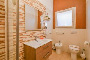 a bathroom with a sink and a toilet and a mirror at Calasole Country House in Torre Lapillo