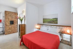 a bedroom with a red bed with a red blanket at Calasole Country House in Torre Lapillo