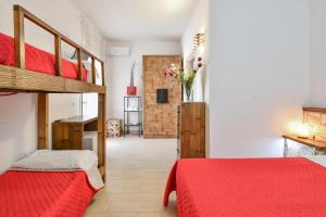 a bedroom with two beds and a red blanket at Calasole Country House in Torre Lapillo