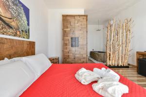 a bedroom with a red bed with towels on it at Calasole Country House in Torre Lapillo