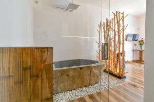 a bathroom with a wooden tub and a glass wall at Calasole Country House in Torre Lapillo