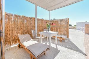 a table with chairs and a vase of flowers on a patio at Calasole Country House in Torre Lapillo