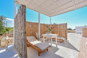 a patio with a white table and chairs and a fence at Calasole Country House in Torre Lapillo