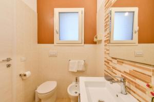 a bathroom with a toilet and a sink and two windows at Calasole Country House in Torre Lapillo