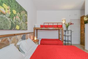 a bedroom with two bunk beds with red sheets at Calasole Country House in Torre Lapillo