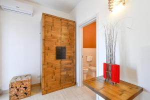 a bathroom with a wooden door with a red vase on a table at Calasole Country House in Torre Lapillo +68 photos