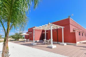 a red building with a table and chairs in front of it at Calasole Country House in Torre Lapillo