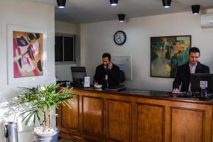 two men are sitting at a reception desk at Hotel Saint Martin in Bauru