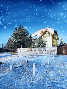 una casa con una cerca blanca en la nieve en Willa Zamkowisko z ogrodowym jacuzzi en Gołubie