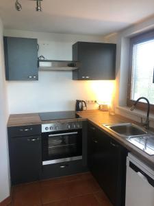uma cozinha com armários pretos, um fogão e um lavatório em Seevilla Matilda direkt am Ufer em Jois