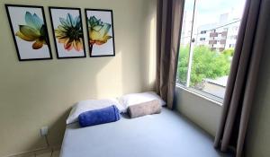 1 dormitorio con 1 cama y una ventana con fotografías en APARTAMENTO CONFORTAVEL em Petrolina 2 quartos com ar cond e Wi-Fi 100MB en Petrolina