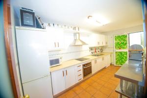 a kitchen with white cabinets and a large refrigerator at Disfruta del paraíso en primera línea de playa con Kayak y Paddle Surf in El Rompido