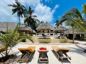 a resort with two tables and umbrellas on the beach at Oleza Boutique Hotel Zanzibar in Michamvi