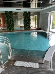 a large swimming pool in a building with two chairs at Apartament Lividus 210 ApartPark in Świnoujście