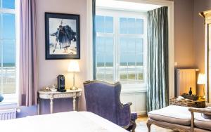 a bedroom with a bed and a chair and windows at La Goélette, Chambres d'Hôtes in Wimereux