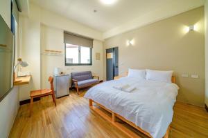 a bedroom with a large white bed and a chair at Ryokou in Hualien City