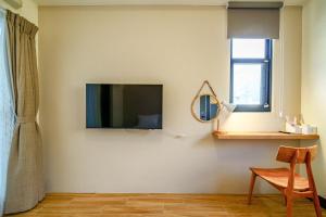 sala de estar con TV de pantalla plana en la pared en Ryokou en Hualien