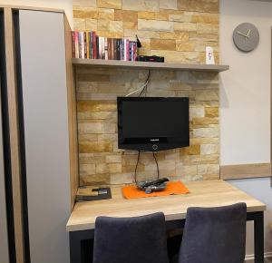 a desk with a tv on a stone wall at Apartman Pahuljica in Kopaonik