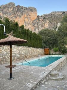 einen Pool mit Sonnenschirm neben einem Berg in der Unterkunft Cortijo el Chorreadero en Parque Natural Sierra de Cazorla in Los Rosales