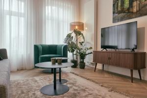 a living room with a television and a green couch at RITCH Hotel Alkmaar in Alkmaar