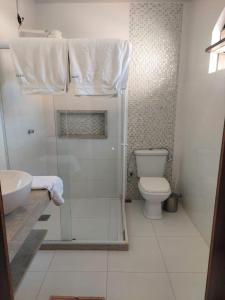 a bathroom with a toilet and a shower with towels at Casa das Dunas in Tamoios