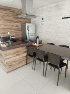 Casa das Dunas في Tamoios: مطبخ مع طاولة وكراسي خشبية كبيرة