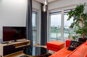 salon z pomarańczową kanapą i dużym oknem w obiekcie Apartament Eveline w mieście Rzeszów