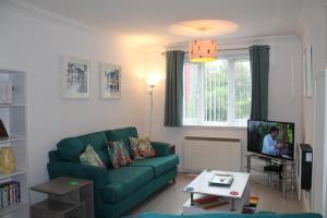 sala de estar con sofá verde y TV en BONNIE'S APARTMENT, adults only, en Bowness-on-Windermere