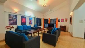 uma sala de estar com sofás azuis e uma mesa em Lifespace- Spacious Hostel in a Luxurious Villa em Pune
