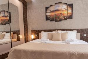 a bedroom with a bed with four paintings on the wall at Apartment Central-LUX in Veliko Tŭrnovo