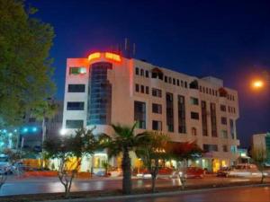 a large building with a neon sign on it at night at Amman Orchid Hotel in Amman